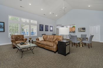 A living room with a brown couch, a glass coffee table, and a ceiling fan.